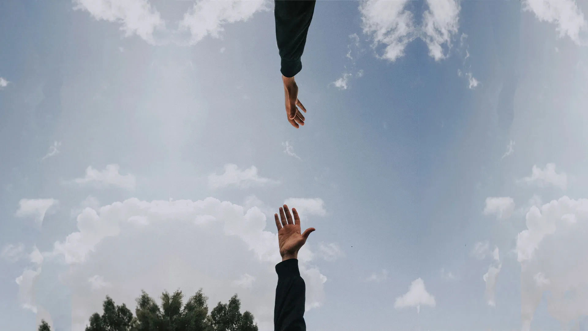 Two hands reaching toward one another across a bright, cloud-filled sky
